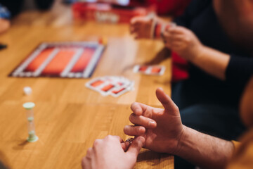Process of playing tabletop board game on the table, fun with friends and family in room indoors,...
