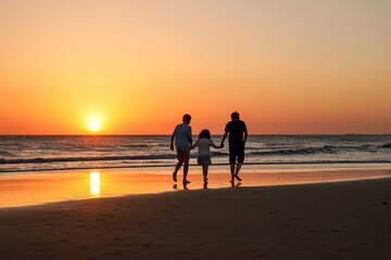 Three kids silhouettes running and jumping on beach at sunset. happy family, two school boys and one little preschool girl. Siblings having fun together. Bonding and family vacation.