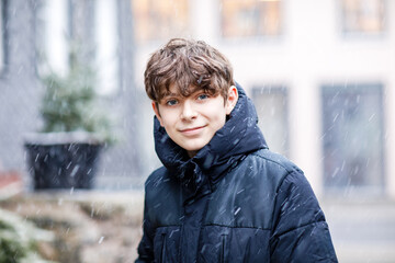 Portrait of teenager school boy outdoors in winter. Beautiful happy child looking at the camera....