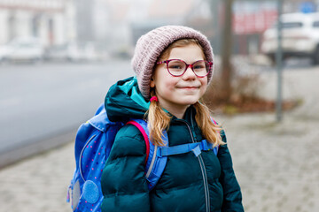 Cute little girl o the way to school. Healthy happy child with eyeglasses walking to primary...