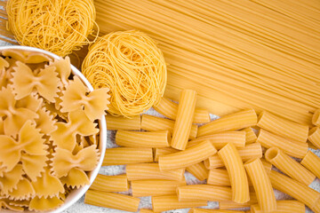 various types of dry pasta. spaghetti, farfalle, rigatoni and vermicelli bunches. The pasta is...