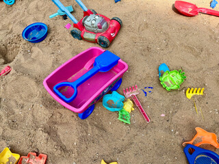 Toys are scattered in a large children's sandbox. Childhood and leisure of kid. Colorful plastic toy