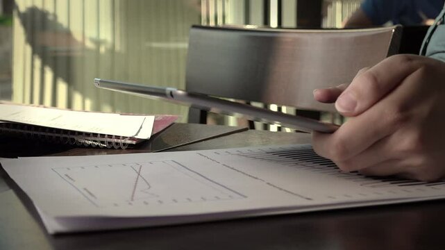 businesswoman working with paper documents and tablet computer in a cafe