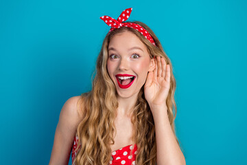 Happy young woman in retro pinup fashion with red polka-dot dress on blue background