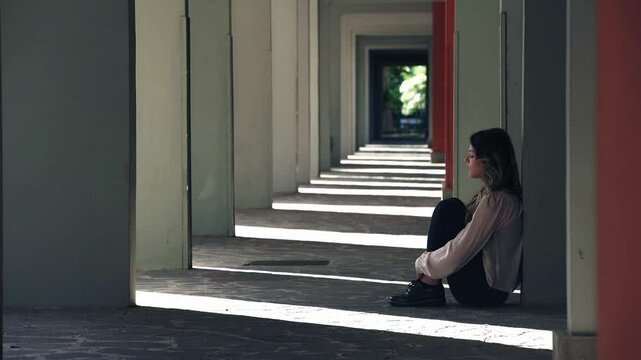 sad depressed woman sitting lonely at the ground of a building 