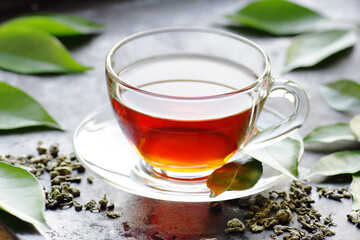 Green chinese tea with fresh leaves, hot drink on black background, closeup, natural medicine and naturopathy concept