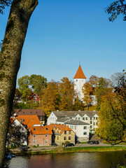 Beautiful view of Talsi Old Town with a white church tower and trees in autumn colors with blue sky © Zigmunds