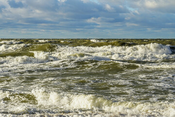 Scenic Baltic sea coastal seascape, stormy sea with big waves, cloudy dark sky, sandy beach