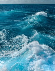 Obraz premium Turquoise ocean water with waves and foam.