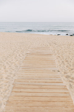 Wooden boardwalk leading to a serene beach with gentle waves