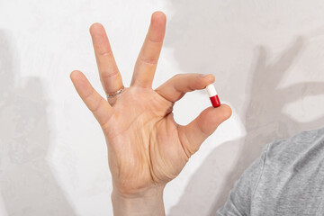 Man holds two-colors capsule. Medications, vitamins, or a sports food supplement. Pill for health