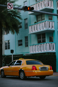 Yellow cab in front of a turquoise building in Miami