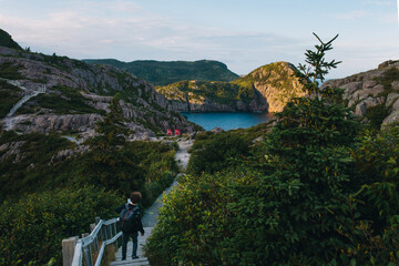 Hiker on coastal pathway overlooking serene bay in Signal Hill, St. John's