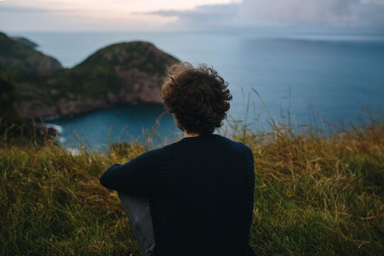Back view of unrecognizable person overlooking coastal scene