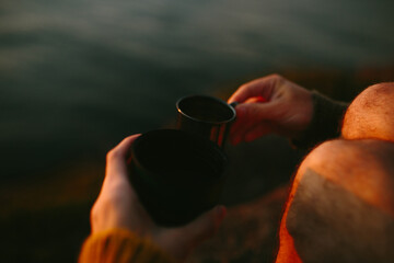 Close-up of anonymous person's hand holding a cup of warm drink at sunset in St. John's