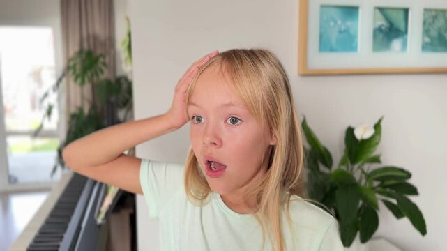 A forgetful blonde girl remembers something after a long time, puts her hand to her forehead, opens her mouth in surprise. A child's poor memory. A blonde-haired little girl gestures that she has