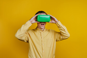 Man in virtual reality headset standing over yellow wall with copy space
