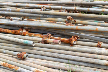 Close-up of a pile of rusty and weathered metal pipes, some showing paint remnants