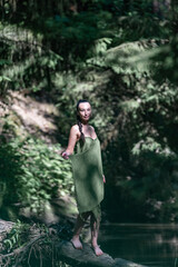 Beautiful young dark-haired girl in a forest river in summer.