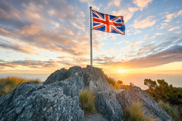 New zealand flag waving on a flagpole at sunrise over scenic rocky landscape