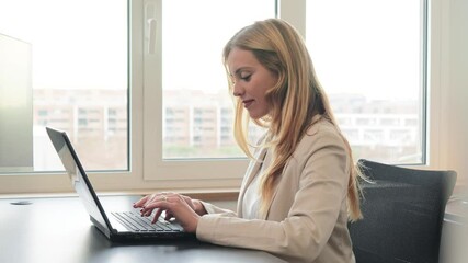 Business woman working with laptop sitting at office desk. Successful executive businesswoman with suit using a computer to analyze the stock market. White collar female worker sending an job e-mail