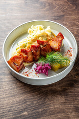 A delicious plate featuring tender grilled meat skewers served over creamy mashed potatoes. Garnished with pickles, red onion, and fresh herbs. Perfect for food photography or culinary use.