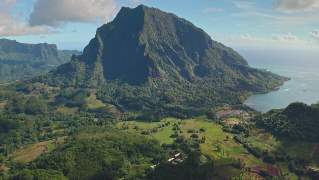 Aerial view revealing stunning beauty of Moorea, French Polynesia, with mount Rotui towering over green hills landscapes and tranquil turquoise water. Wild travel destination, remote nature paradise