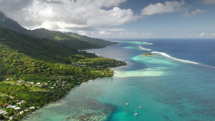 Breathtaking aerial view of Moorea, French Polynesia, vibrant turquoise lagoon, coral reefs, lush green mountains, and sailboats idyllic seascape under a cloudy sky. Remote exotic summer travel scene