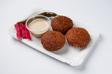 Falafel of legumes typical Middle Eastern traditional dish served on a tray with sauce and resting on a white background