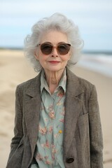 Elderly Woman Enjoying a Beach Stroll in Stylish Attire and Sunglasses