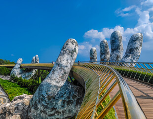 Golden Bridge in Ba Na hills, Da Nang, Vietnam on a sunny day. Lifted by two giant concrete hands. Iconic world famous bridge in the mountains