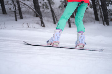 A snowboarder's ascent up a ski slope on a T-bar. Fragment: feet on a snowboard close-up.