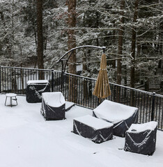 outdoor furniture in back yard covered in snow (poolside patio couch chair coffee table) chairs seating cushion cover protection from elements rain wind snowy weather (folded umbrella) fenced area