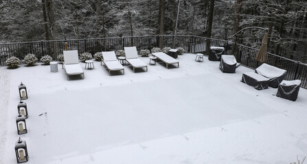 snow covered lounge chairs surrounding a shuttered swimming pool in winter (looking down aerial)...