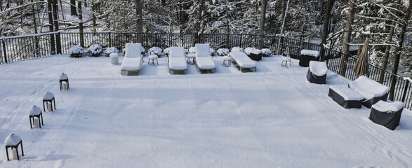 snow covered lounge chairs surrounding a shuttered swimming pool in winter (looking down aerial) back yard patio blizzard snowy weather outdoor furniture cover covered in ground built in off season 
