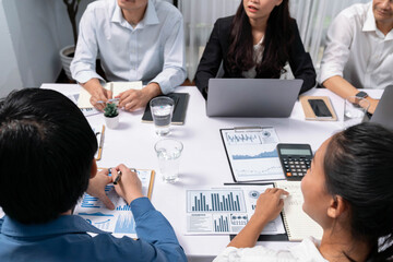 Fototapeta premium Analyst team utilizing BI Fintech to analyze financial data at table in meeting room. Businesspeople analyzing BI dashboard power on paper for business insight and strategic marketing planning.Prudent