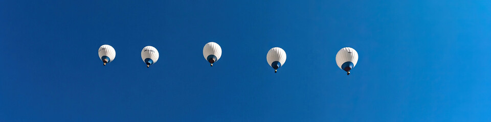 Five Hot Air Balloons in Flight Against a Blue Sky
