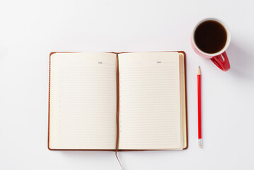 Brown notebook, red pencil and red cup with coffee on white background. Morning plans for the day, workspace. Productivity and concentration concept