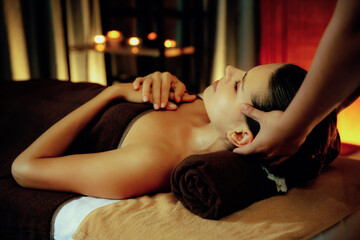 Fototapeta premium Caucasian woman enjoying relaxing anti-stress head massage and pampering facial beauty skin recreation leisure in warm candle lighting ambient salon spa in luxury resort or hotel. Quiescent