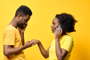 Young couple engaged in a romantic conversation over the phone, showcasing emotions of love and connection against a vibrant yellow background