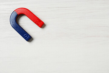 One horseshoe magnet on white wooden background, top view. Space for text