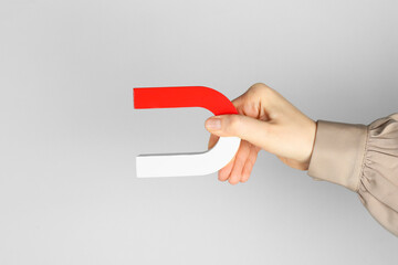 Woman with horseshoe magnet on grey background, closeup