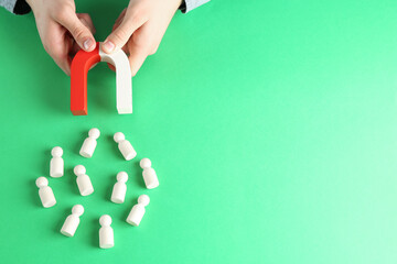 Man with magnet attracting game pieces at green table, above view. Space for text