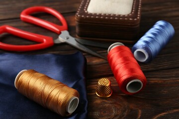 Different sewing supplies on wooden table, closeup
