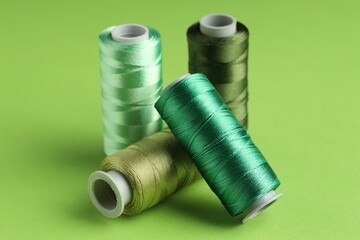 Spools of sewing threads on green background, closeup