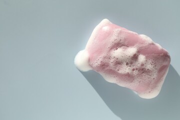Soap bar with foam on grayish blue background, top view. Space for text