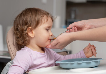 A toddler being lovingly fed by their caregiver during mealtime.
