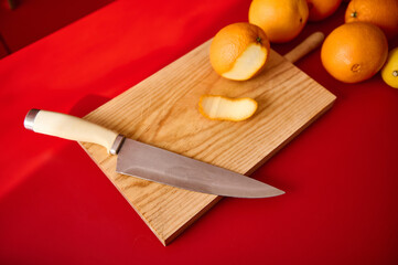 Wooden cutting board with knife and oranges in a vibrant kitchen setting