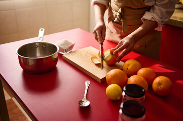 Person preparing citrus fruits for cooking on a red kitchen counter