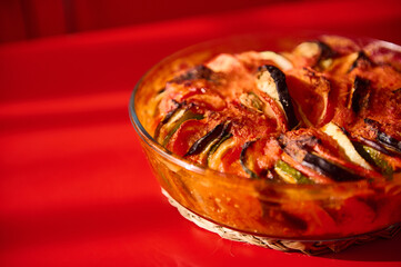 Close-up of a baked ratatouille dish in a vibrant red background